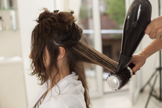 young woman in a hair salon. drying and shaping the hair with a blow dryer and brush