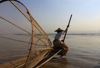 Poster Burmese fisherman on bamboo boat catching fish in traditional way with handmade net. Inle lake, Myanmar (Burma) © AnastasiiaUsoltceva