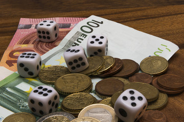 dice, coins, euro banknotes on a wooden table