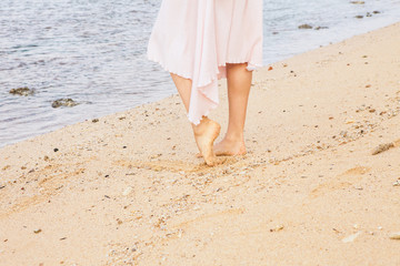 Woman legs walking on the beach sand