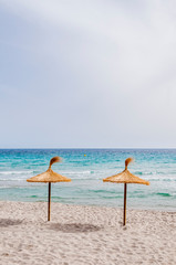 Straw umbrellas on sand beach.