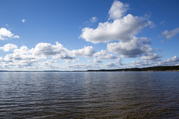 Naklejka na ściany i meble Beautiful summer view. Image taken in Finland on a summer afternoon with blue sky and clouds. Clouds are reflecting from the water.