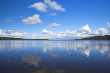 Beautiful summer view. Image taken in Finland on a summer afternoon with blue sky and clouds. Clouds are reflecting from the water.
