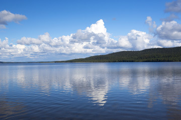 Beautiful summer view. Image taken in Finland on a summer afternoon with blue sky and clouds. Clouds are reflecting from the water.