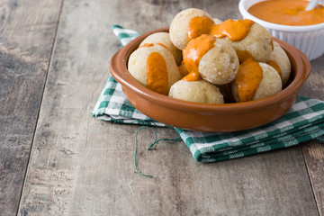 Canarian potatoes (papas arrugadas) with mojo sauce on wooden table

