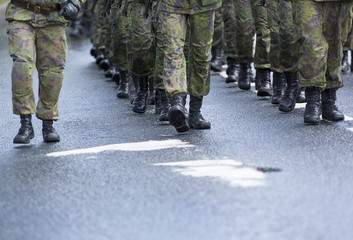 Soldiers marching on the asphalt road. Image of black boots and camouflage clothes.