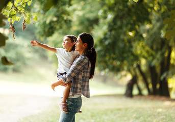 Fototapeta premium Mother holding her daughter and playing around the park on beautiful morning.