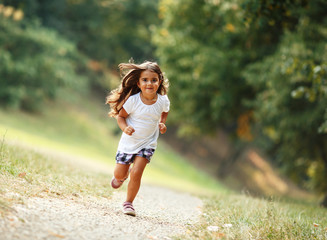 Little girl running through the park.	