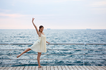Fototapeta na wymiar Young beautiful ballerina dancing and posing outside, sea background.