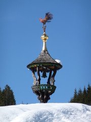 Fototapeta na wymiar Wooden bell tower with cockerel in a village in the Austrian Alps