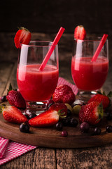 Glasses of fresh cold smoothie with fruit and berries, on wooden background, healthy detox drink