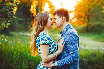 Lovers having touched their heads are in the last rays of the sun on the field.