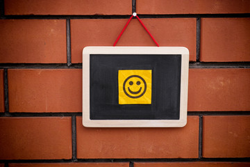Paper note with happy face on blackboard