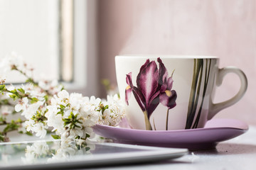 Hot drink cup beside window whith spring flower