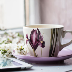 Hot drink cup beside window whith spring flower