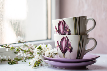  tea set, a bouquet of spring flowers  near  the window
