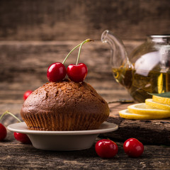 Tasty muffin with cherry and mint on vintage wooden background