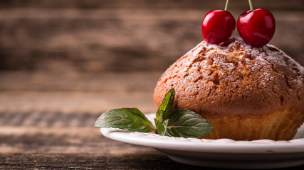 Tasty muffin with cherry and mint on vintage wooden background