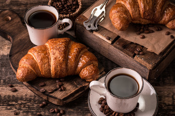 Breakfast with coffee and croissants on wooden vintage table