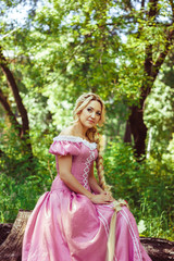 Obraz na płótnie Canvas Beautiful girl with long hair braided in a braid, in corset and magnificent pink dress.