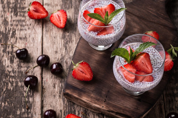 chia seed pudding with strawberries and min on wooden vintage background