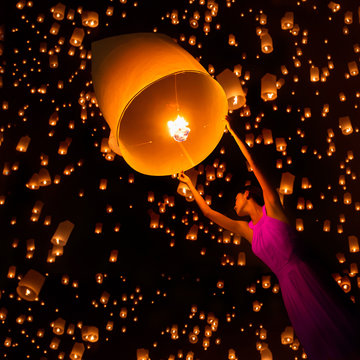 Young woman release sky lanterns to worship buddha's relics in yi peng festival, Chiangmai thailand