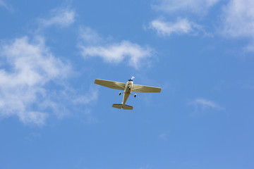 Small airplane flying above against a blue sky.
