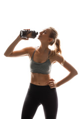 Beautiful sportive girl holding bottle, posing over white background.