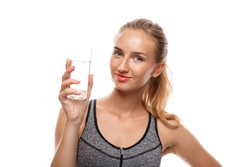 Beautiful sportive girl posing, holding glass of water over white background.