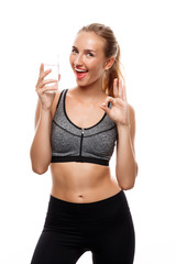 Beautiful sportive girl posing, holding glass of water over white background.