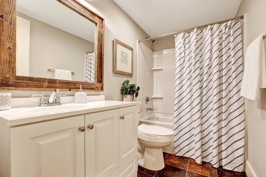 White Bathroom with vanity cabinet and wooden framed mirror.