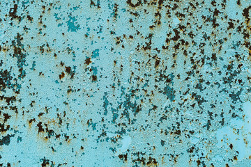 Old rusty metal surface is covered with several layers of peeling paint of different colors. background