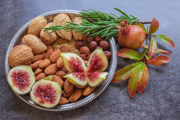 Plate with a variety of nuts and figs. Sprigs of rosemary and po