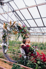 Fototapeta na wymiar Woman in red cloud dress with man hugging and embracing in greenhouse. 