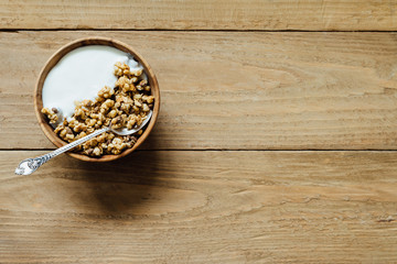 Homemade oatmeal granola with yogurt in wooden bowl