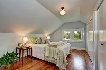 Attic bedroom interior with vaulted ceiling and hardwood floor.