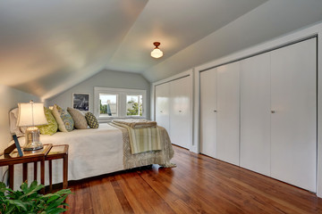 Attic bedroom interior with vaulted ceiling and hardwood floor.