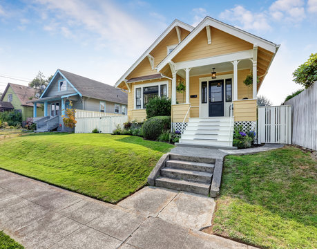 American craftsman home with yellow exterior paint.