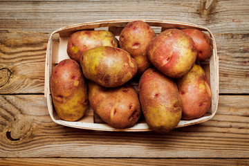 potatoes in wooden crate on rustic wooden table, top view