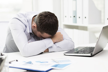 businessman with laptop and papers in office