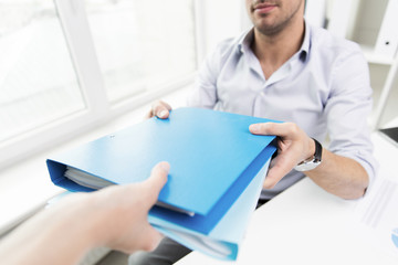 close up of businessman taking folders from hand