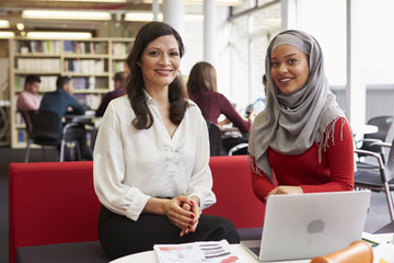 Female University Student Working In Library With Tutor