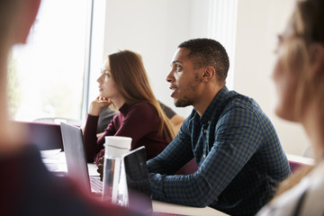 Students At Desks Attending Lecture On Campus