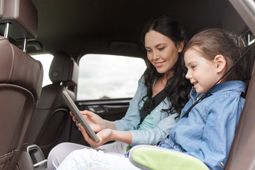 happy family with tablet pc driving in car