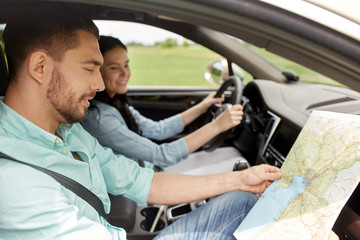 happy man and woman with road map driving in car