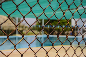 A blur picture of a swimming pool behind the wire mesh.