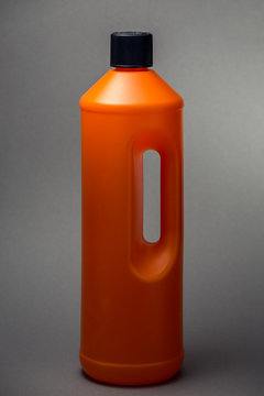 Orange Plastikflasche f&uuml;r Reinigungsmittel vor grauem Hintergrund
