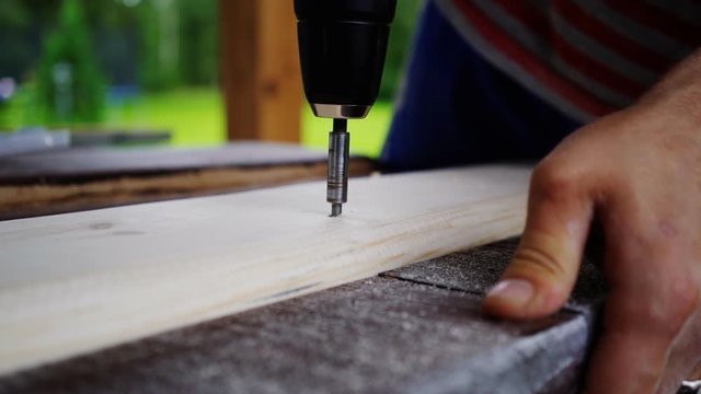 carpenter drill to drill holes in the board. hands closeup