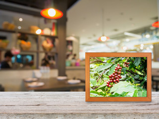 Coffee plantation in photo frame on wood counter over Blur coffe