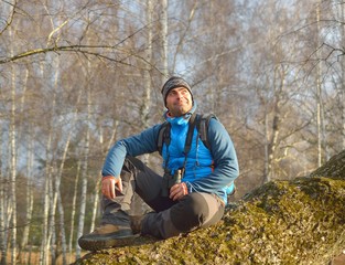 man with backpack hiking resting on a trunk in forest